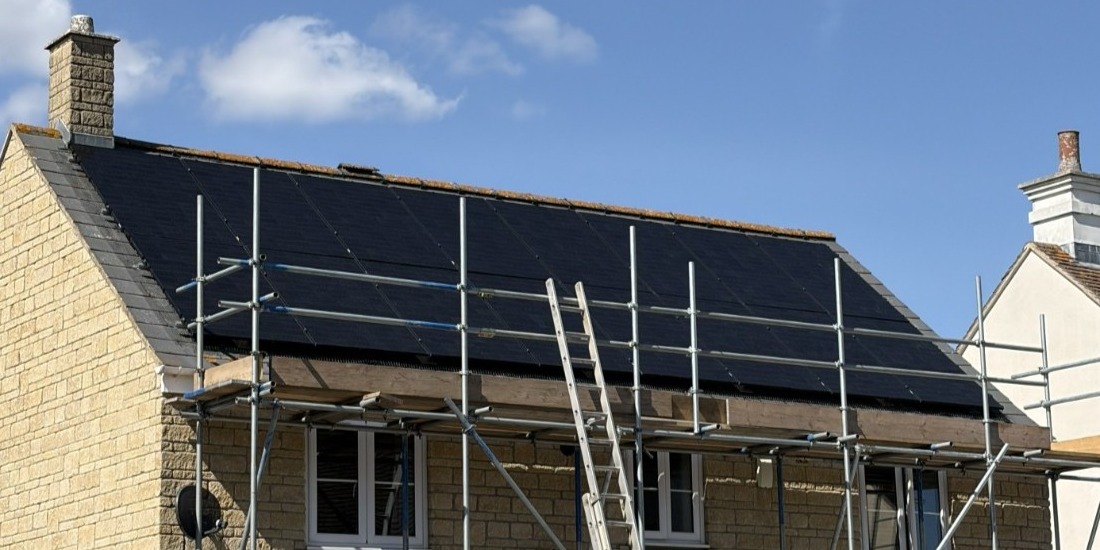 Solar panels installed on the roof of a stone home in England, photographed by Cozy Home Solutions.
