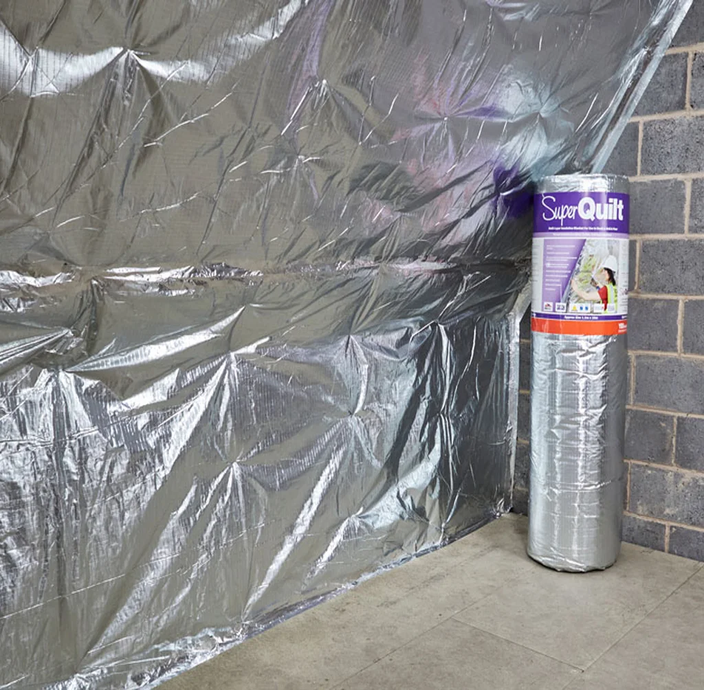 YBS SuperQuilt multifoil insulation fitted across a sloped ceiling and knee wall, with a wrapped roll standing ready to fit.